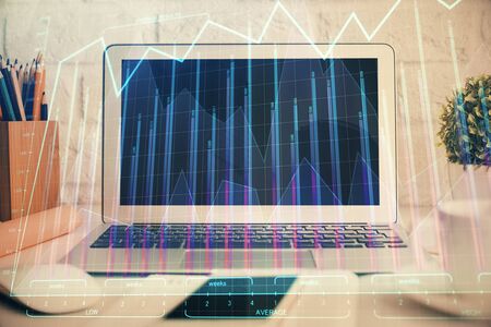 Stock market graph on background with desk and personal computer. Multi exposure. Concept of financial analysis.の写真素材