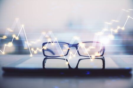Financial graph hologram with glasses on the tableの写真素材