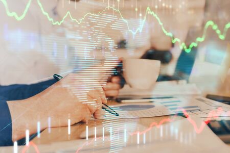 Double exposure of mans hands writing notes of stock market with forex graph.の写真素材