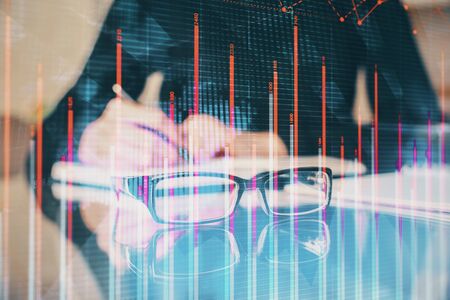 Forex chart hologram on hand taking notes background. Concept of analysis. Multi exposure