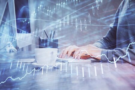 Multi exposure of graph with man typing on computer in office on background. Concept of hard work.