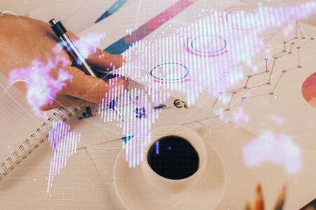 Double exposure of Man writing in notepad with business icons on background.の写真素材