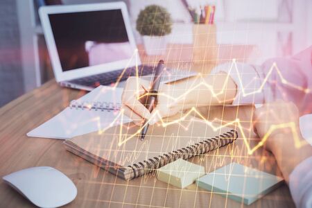 Financial charts displayed on womans hand taking notes background. Concept of research. Double exposureの写真素材
