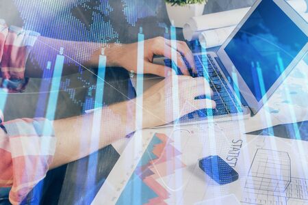 Double exposure of stock graph with businessman typing on computer in office on background. Concept...