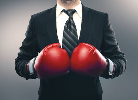 Businessman in red boxing gloves isolated on gray background. Business challenge conceptの写真素材