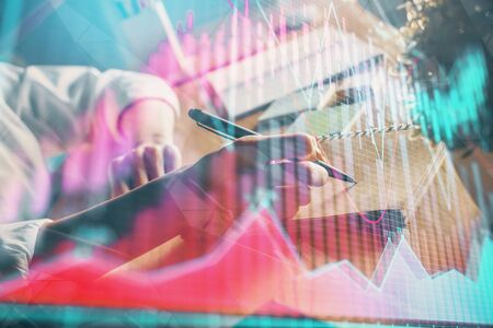 Financial forex charts displayed on womans hand taking notes background. Concept of research. Double...