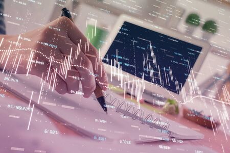 Financial forex graph drawn over hands taking notes background. Concept of research. Double exposureの写真素材