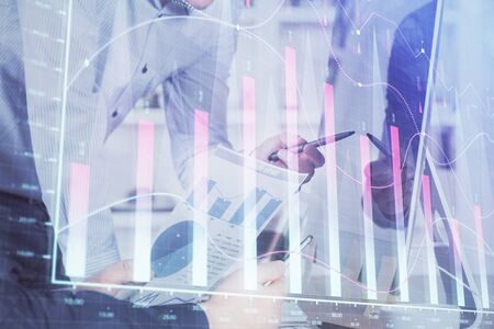 Double exposure of chart with businessman typing on computer in office on background. Concept of hard work.の写真素材