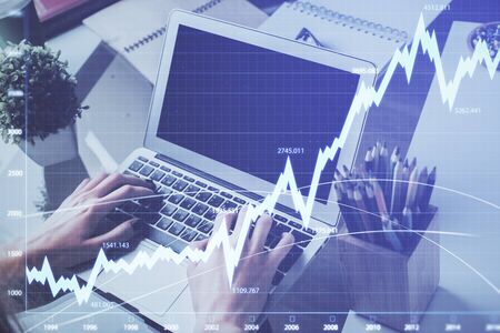 Double exposure of mans hands writing notes with laptop of stock market with forex graph background....
