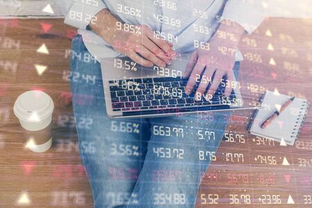 Double exposure of mans hands writing notes with laptop of stock market with forex graph background....