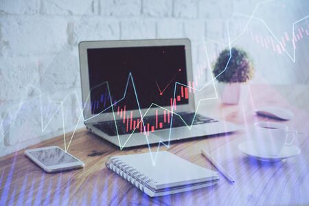 Stock market graph on background with desk and personal computer. Multi exposure. Concept of financial analysis.の写真素材