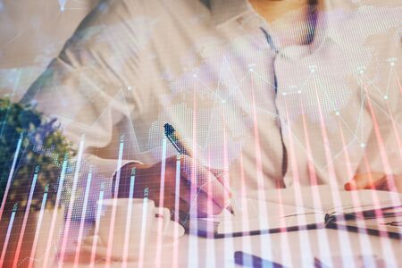 Double exposure of mans hands writing notes of stock market with forex chart.の写真素材