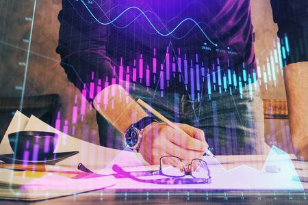 Double exposure of man writing on paper with forex graph.
