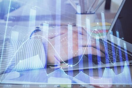 Multi exposure of stock market graph with man working on laptop on background. Concept of financial...