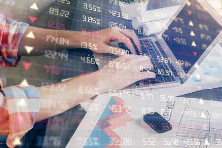Double exposure of stock graph with businessman typing on computer in office on background. Concept...