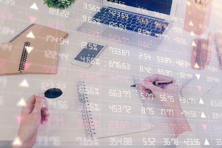 Hands writing information about stock market in notepad. Forex chart holograms in front. Concept of research. Multi exposureの写真素材