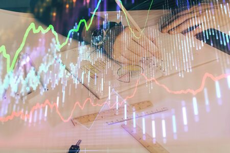 Double exposure of mans hands writing notes of stock market with forex chart.の写真素材