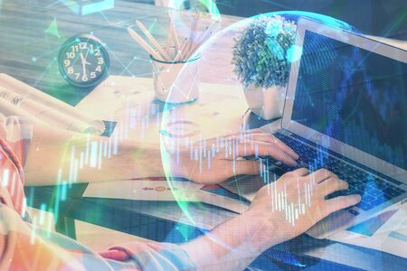 Double exposure of stock graph with businessman typing on computer in office on background. Concept of hard work.の写真素材