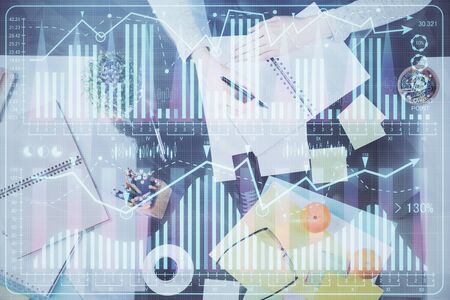 Hand taking notes in notepad. Forex chart holograms in front. Concept of research. Double exposureの写真素材