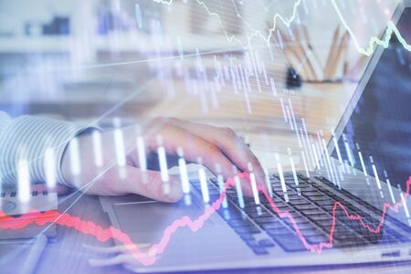 Double exposure of mans hands writing notes with laptop of stock market with forex graph background....