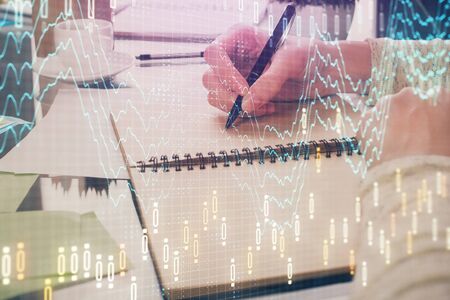 Forex chart hologram on hand taking notes background. Concept of analysis. Double exposureの写真素材