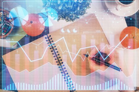 Forex chart hologram on hand taking notes background. Concept of analysis. Double exposureの写真素材