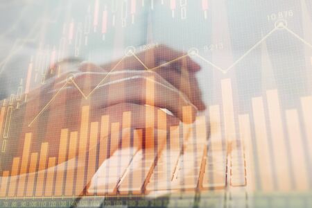 Double exposure of graph with man typing on computer in office on background. Concept of hard work....