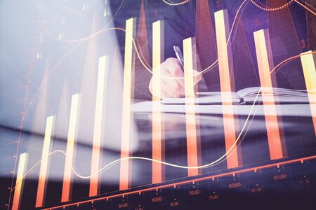 Double exposure of businessman's hands with laptop and stock market graph background. Concept of research and trading.の写真素材
