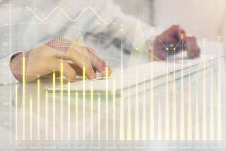 Double exposure of graph with man typing on computer in office on background. Concept of hard work. Closeup.の写真素材