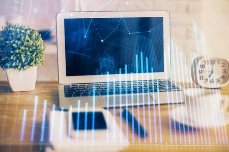 Forex market graph hologram and personal computer on background. Double exposure. Concept of investment.の写真素材