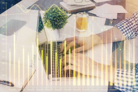 Multi exposure of graph with man typing on computer in office on background. Concept of hard work. Closeup.の写真素材