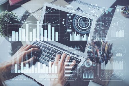 Double exposure of businessmans hands with laptop and stock market graph background. Concept of research and trading.の写真素材