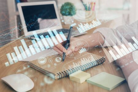 Financial charts displayed on womans hand taking notes background. Concept of research. Double exposureの写真素材