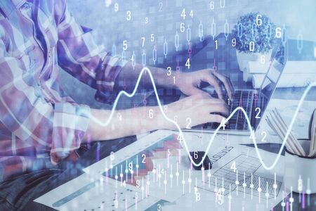 Double exposure of stock graph with businessman typing on computer in office on background. Concept of hard work.の写真素材