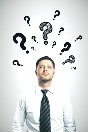 Businessman with drawing question mark over head on gray background. Business confusion conceptの写真素材