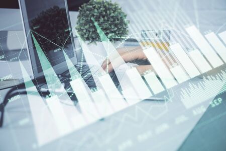 Multi exposure of graph with man typing on computer in office on background. Concept of hard work. Closeup.の写真素材