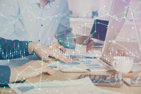 Multi exposure of chart with man typing on computer in office on background. Concept of hard work.