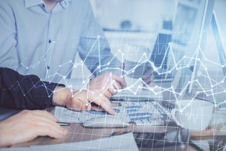 Multi exposure of chart with man typing on computer in office on background. Concept of hard work.