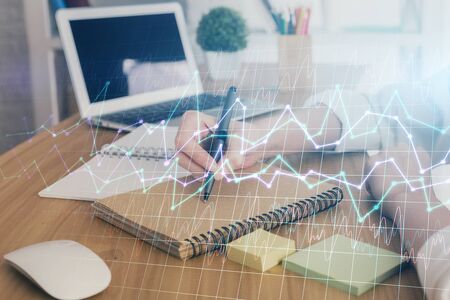 Financial charts displayed on womans hand taking notes background. Concept of research. Double exposureの写真素材