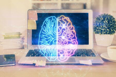 Double exposure of table with computer and brain hologram. Data innovation concept.