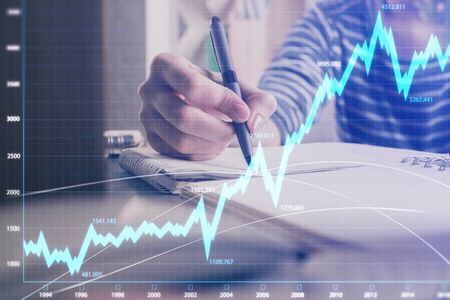 Financial forex graph drawn over hands taking notes background. Concept of research. Double exposure