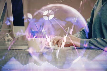 Multi exposure of graph with man typing on computer in office on background. Concept of hard work.の写真素材