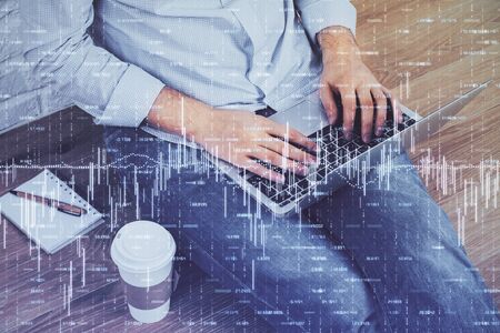 Double exposure of businessmans hands with laptop and stock market graph background. Concept of...