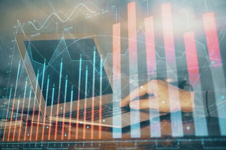 Double exposure of businessman's hands with laptop and stock market graph background. Concept of research and trading.の写真素材