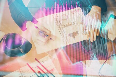 Multi exposure of hands making notes with forex chart huds. Stock market concept.の写真素材