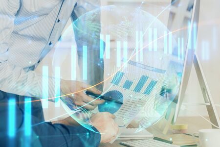 Double exposure of chart with businessman typing on computer in office on background. Concept of hard work.の写真素材