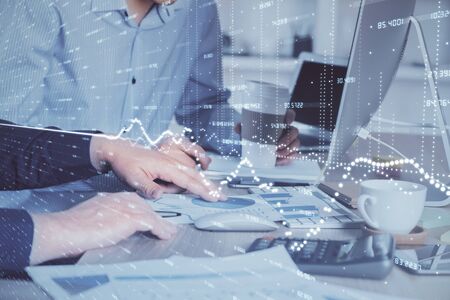 Multi exposure of chart with man typing on computer in office on background. Concept of hard work.