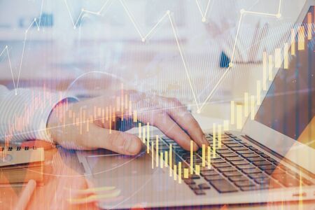 Multi exposure of market chart with man working on computer on background. Concept of financial...