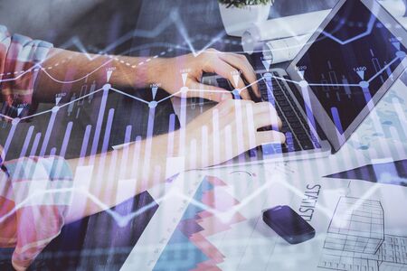 Double exposure of stock graph with businessman typing on computer in office on background. Concept of hard work.の写真素材