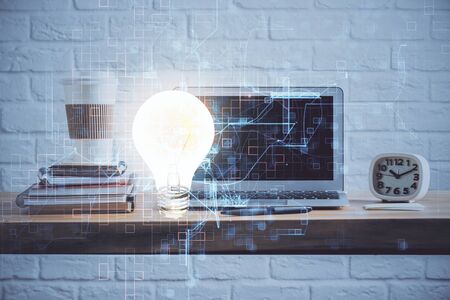 Computer on desktop in office with bulb icon hologram. Multi exposure. Concept of idea.の写真素材